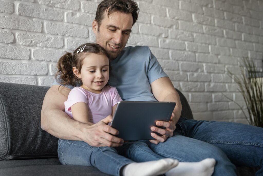 Father and daughter playing on a tablet.